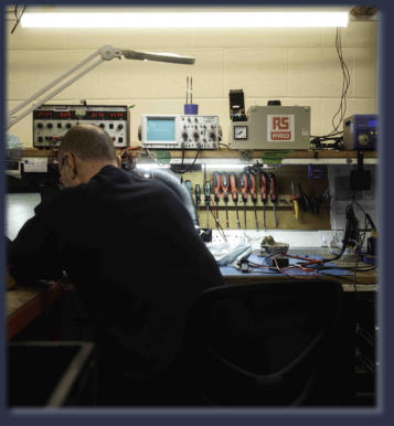 Technician performing industrial electronic repair on PLC unit at Neutronics NE Ltd