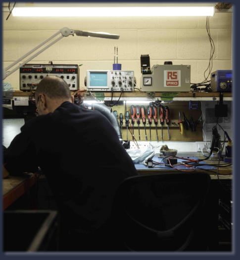 Technician performing industrial electronic repair on PLC unit at Neutronics NE Ltd