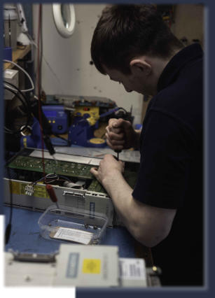 Neutronics engineer repairing industrial electronic control unit at workstation