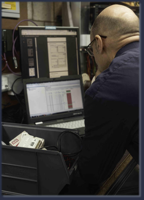 Neutronics engineer analysing diagnostic data and schematics on dual monitors during electronics training session
